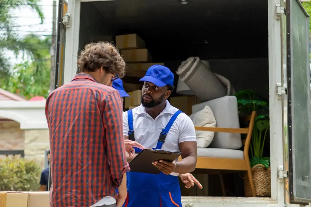 Removal service worker speaking with a customer beside a truck